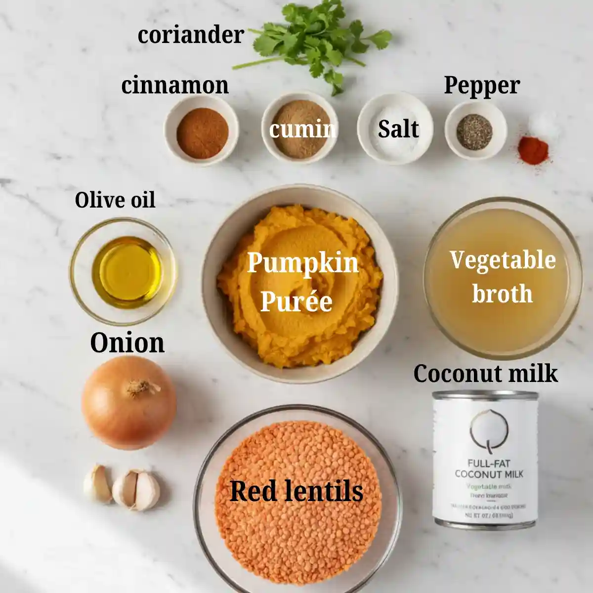 Whole ingredients for creamy vegan pumpkin and red lentil soup, including pumpkin purée, lentils, coconut milk, broth, onion, garlic, and spices.