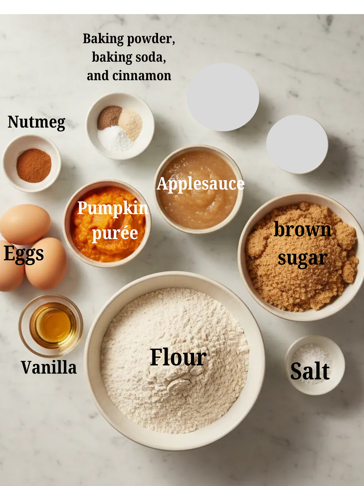 Overhead flat lay of ingredients for a healthy pumpkin applesauce cake, including pumpkin purée, unsweetened applesauce, whole wheat flour, brown sugar, eggs, vanilla, and warm spices on a light marble surface.
