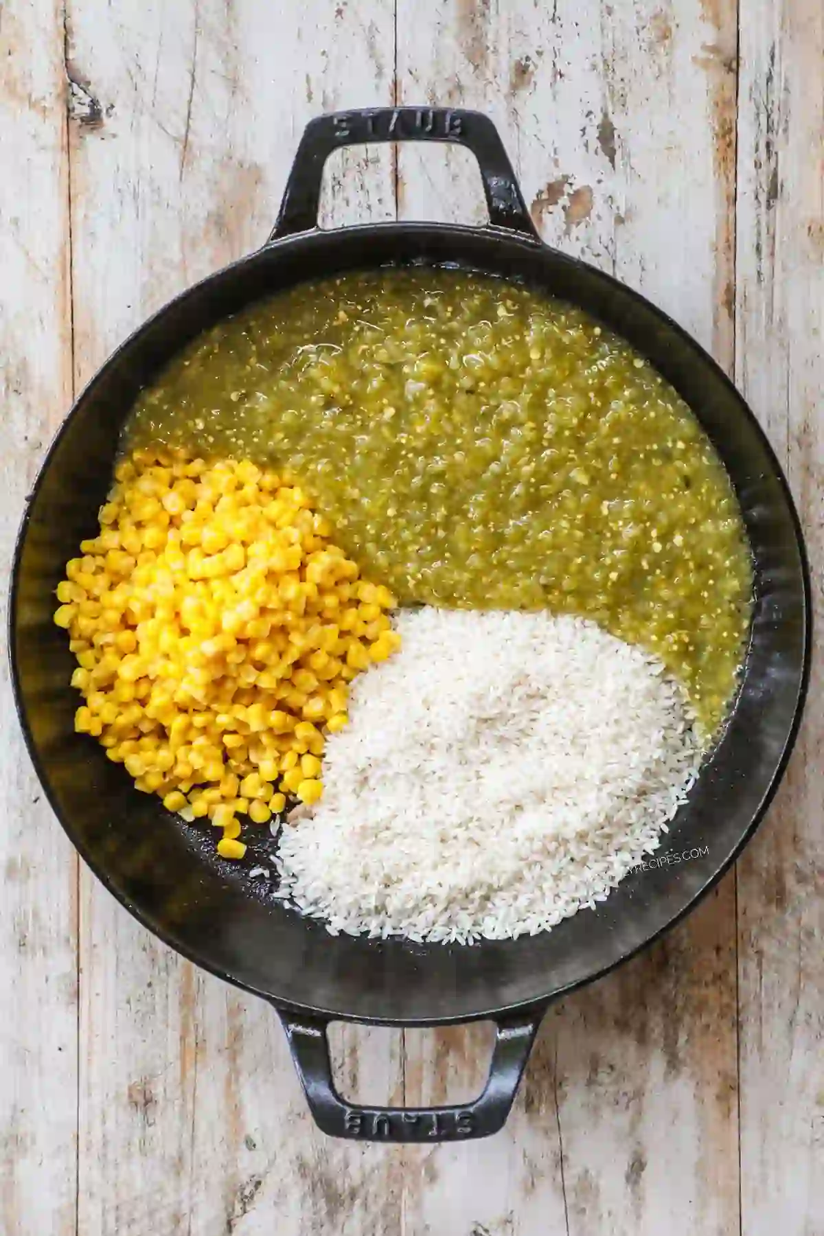 Rice, corn, and salsa verde added to a skillet after searing chicken.