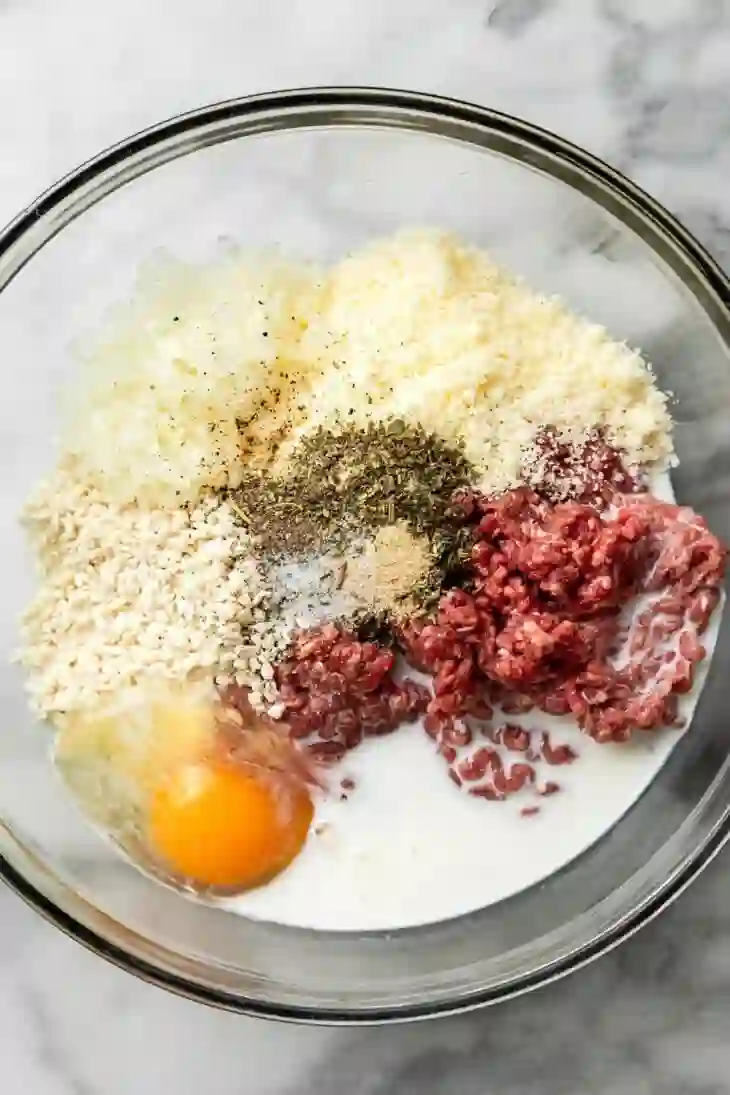 baked-italian-meatballs-step-1-ingredients-in-bowl._compressed Ingredients for baked Italian meatballs layered in a glass bowl before mixing