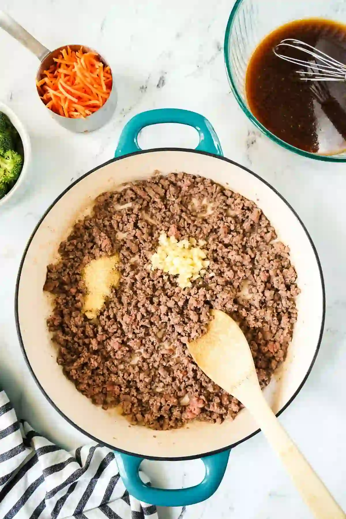 Ground beef browning in a skillet with garlic and seasonings added