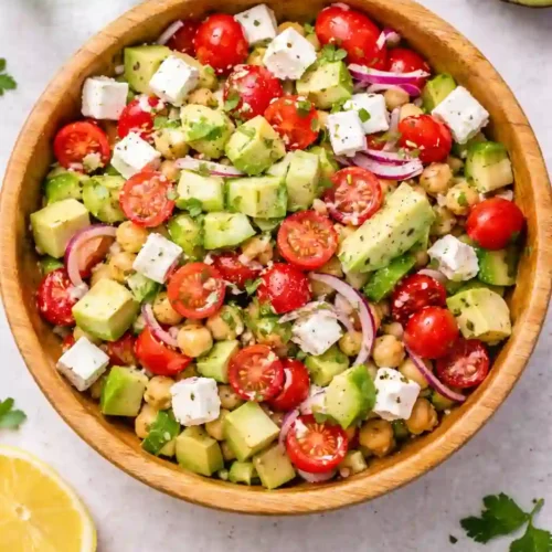 Chickpea feta avocado salad in a wooden bowl with fresh vegetables