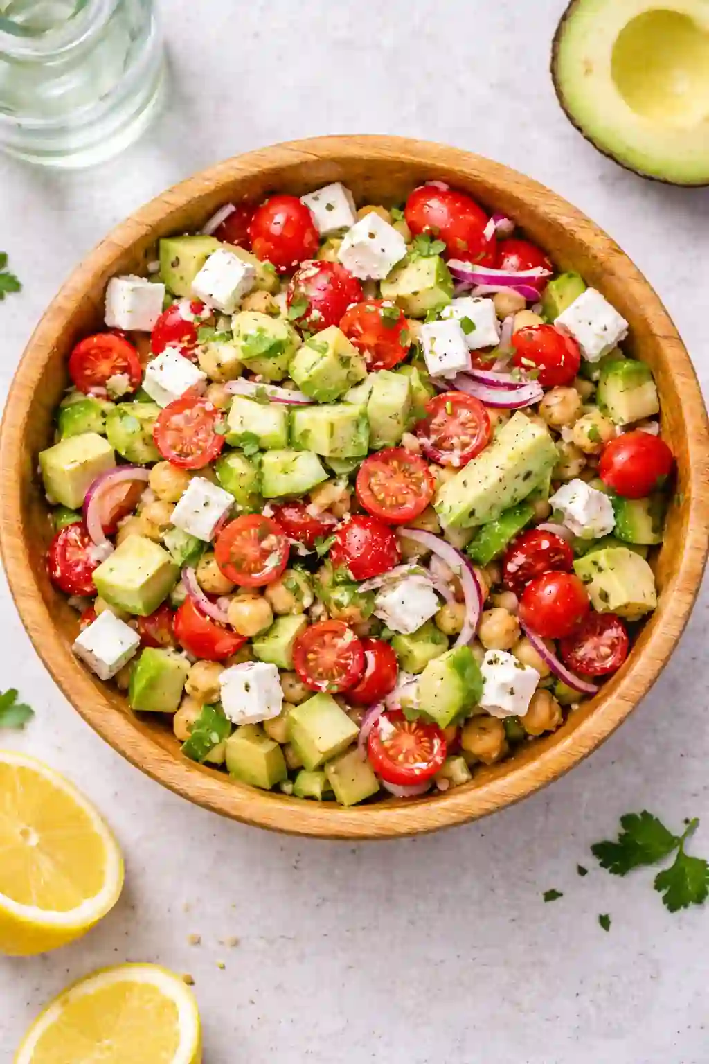 Chickpea feta avocado salad in a wooden bowl with fresh vegetables