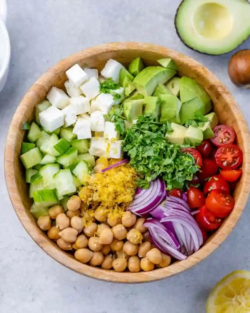 Chickpea feta avocado salad ingredients arranged in a bowl before mixing