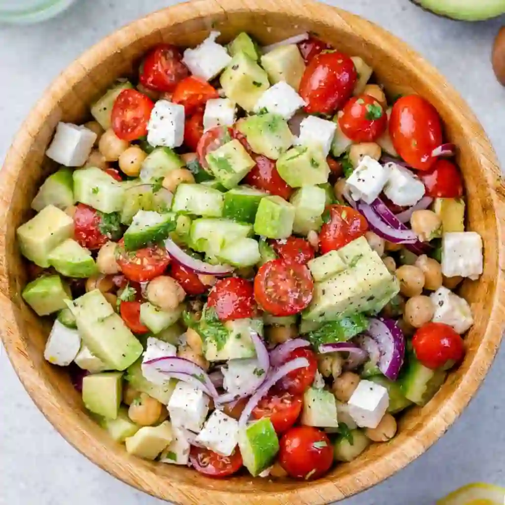 Finished chickpea feta avocado salad mixed with lemon and seasoning in a wooden bowl