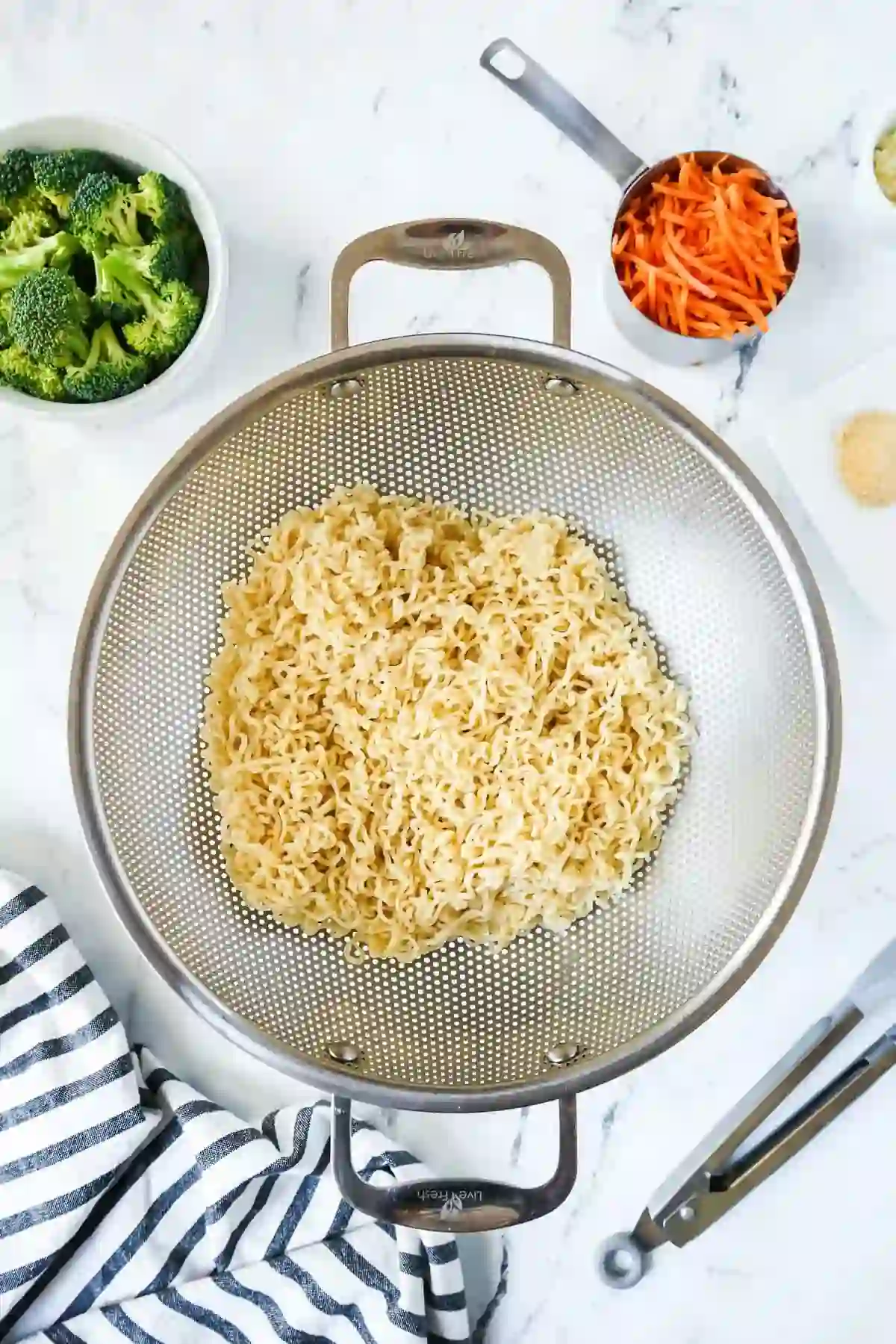 Rinsed ramen noodles draining in a colander after boiling for stir fry