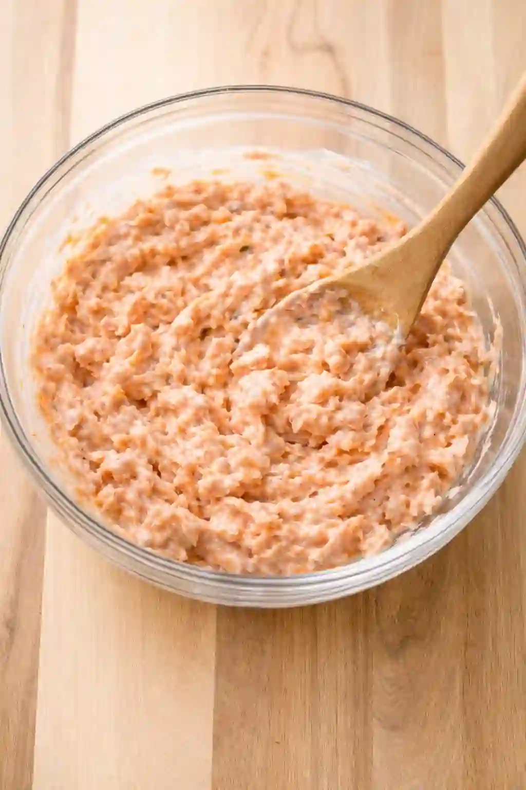 Creamy salmon mixture being stirred in a glass bowl
