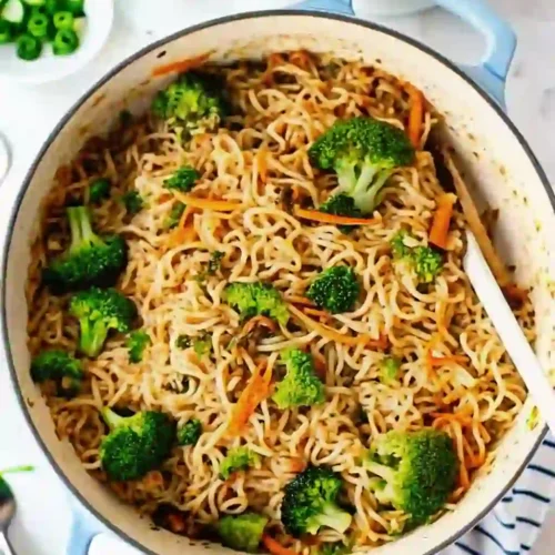 Ground beef noodle stir fry with ramen, broccoli, and carrots in a skillet