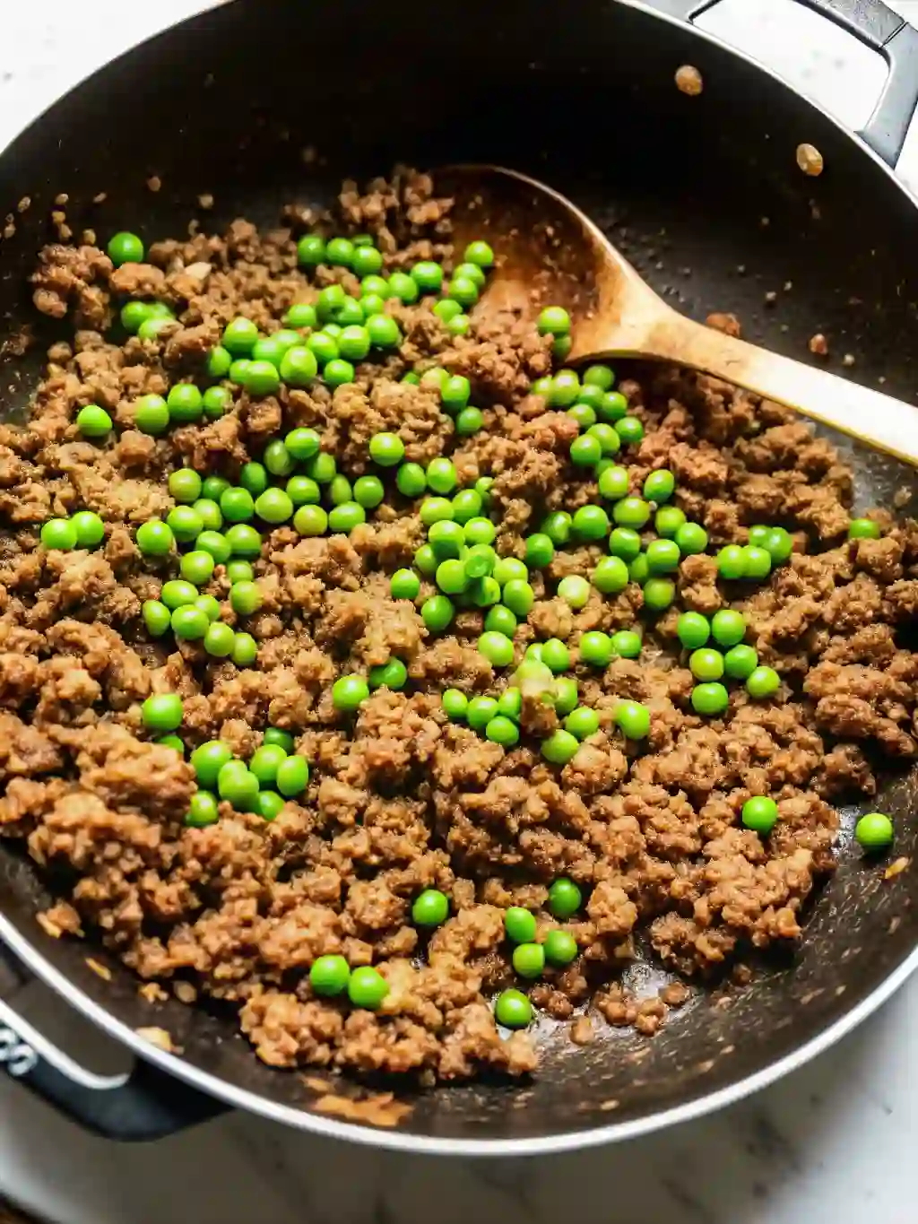 Overhead view of glazed soboro ground beef with peas in skillet