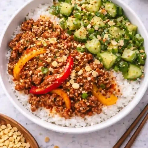 Overhead Korean gochujang beef bowl with rice, cucumber salad, and peanuts