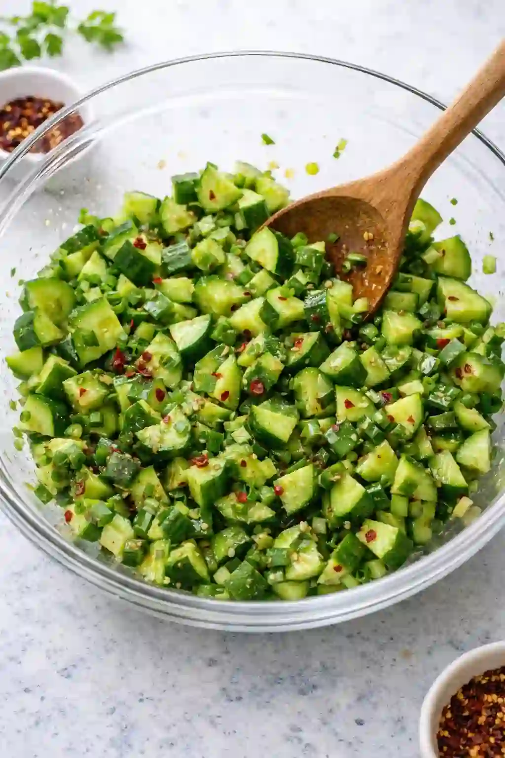 Mixing cucumber salad with ginger juice and green onions in a bowl