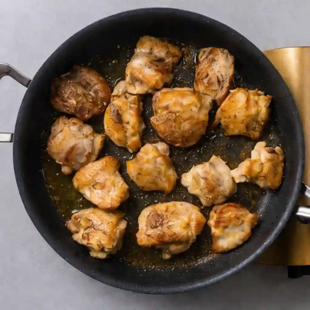 mediterranean-chicken-orzo-step-1-prep-sear._compressed Golden-brown chicken thighs searing in olive oil in a large skillet