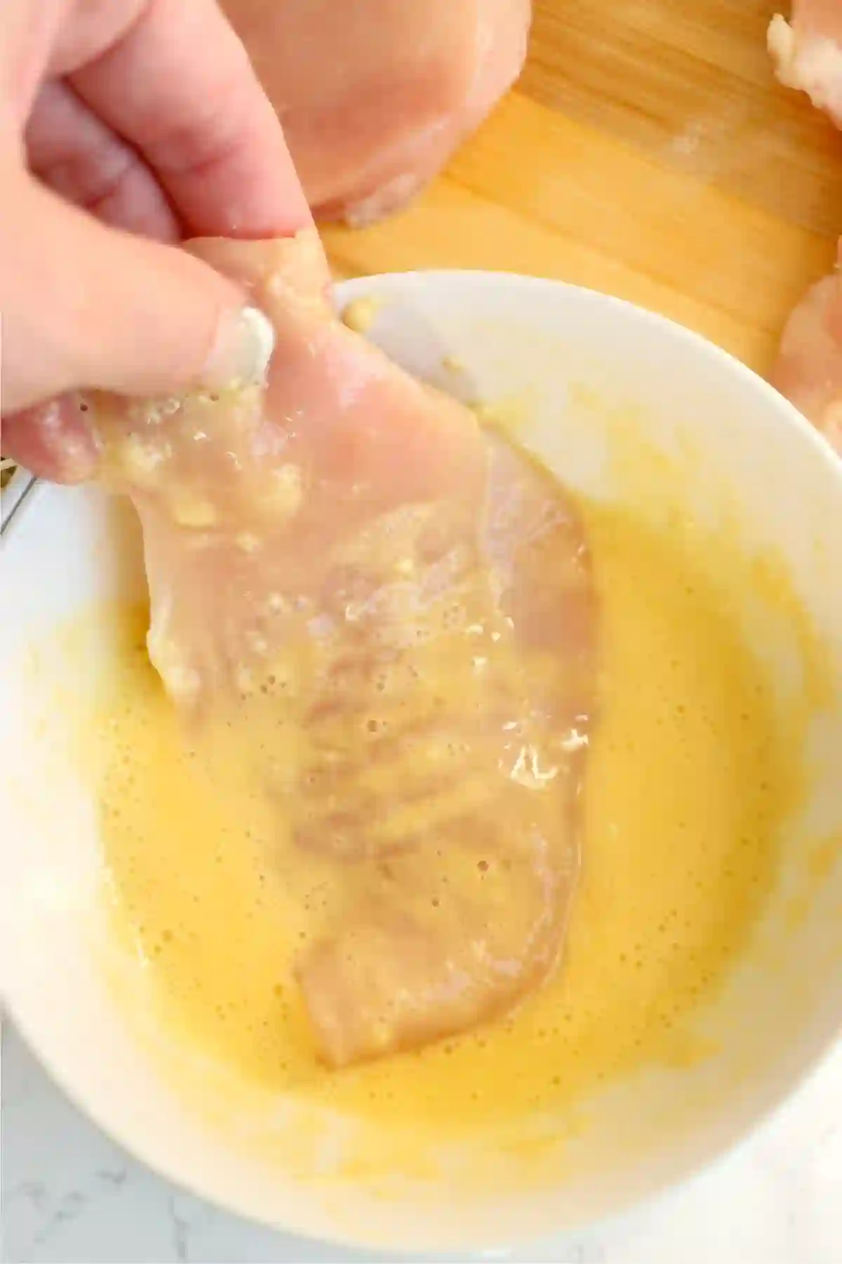 step-1-dredge-chicken-egg-wash._compressed Chicken breast being dredged in egg wash