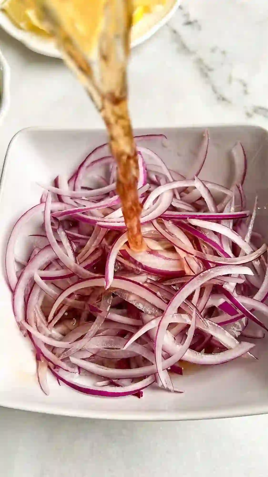 step-1-pickle-red-onions._compressed Pouring vinegar over sliced red onions to make quick pickled onions.