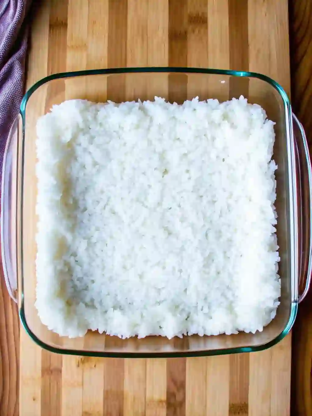 Seasoned sushi rice pressed evenly into a glass baking dish