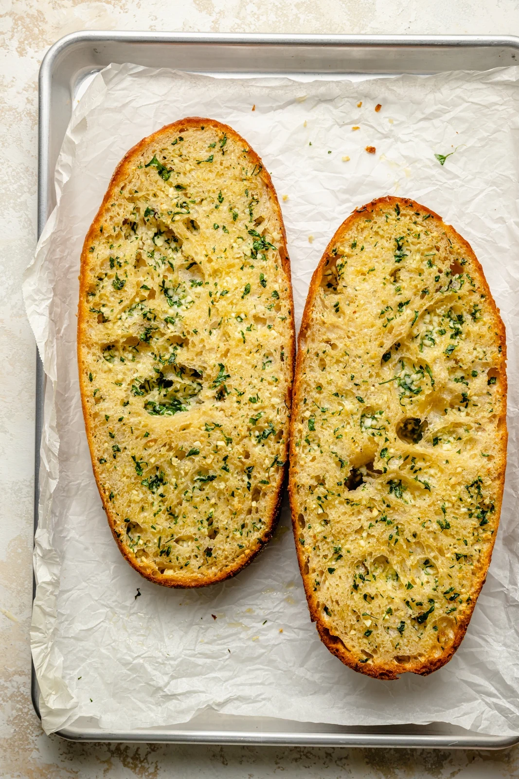 Garlic-Bread Baked garlic bread with golden edges and herbs on a parchment-lined baking sheet