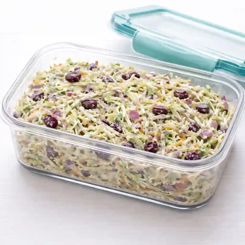 Broccoli slaw stored in an airtight container on a white table