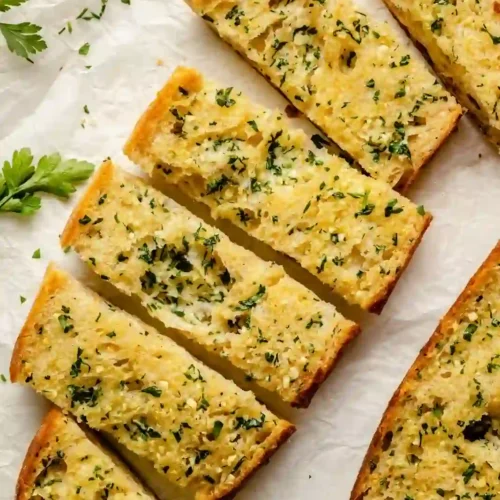 Homemade Crusty Garlic Bread That’s Perfectly Crisp 1 Sliced crusty garlic bread with golden edges and buttery garlic topping on parchment paper