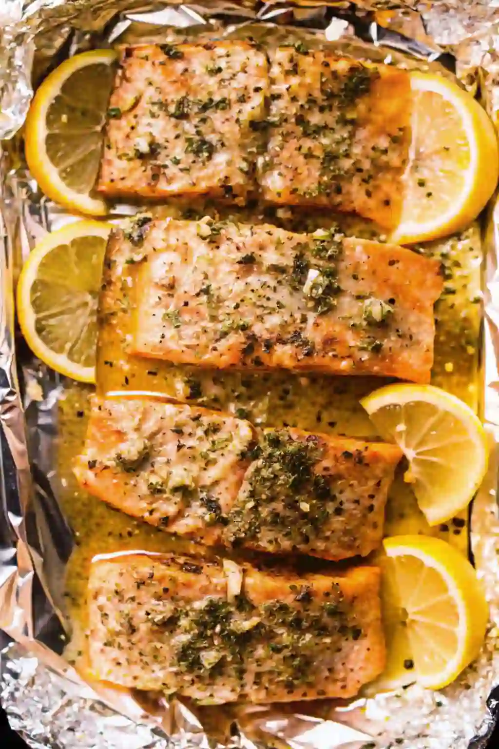 lemon-garlic-butter-baked-salmon-image-2_compressed Overhead baked salmon with lemon butter cream sauce in foil packet with lemon wedges