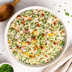 Old fashioned pea salad recipe with mayonnaise served in a white ceramic bowl, overhead view