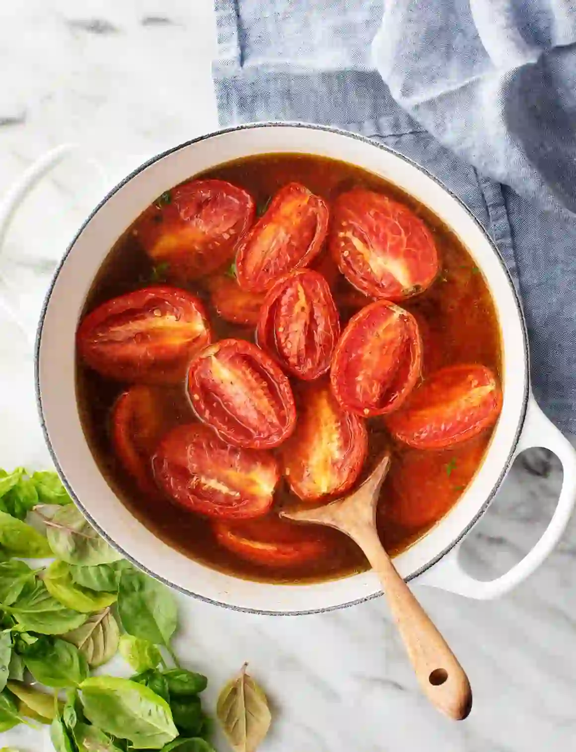 Roasted roma tomatoes simmering in a pot with broth and herbs, ready to be blended into tomato basil soup
