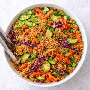 Overhead view of chicken crispy rice salad with peanut dressing in a white bowl