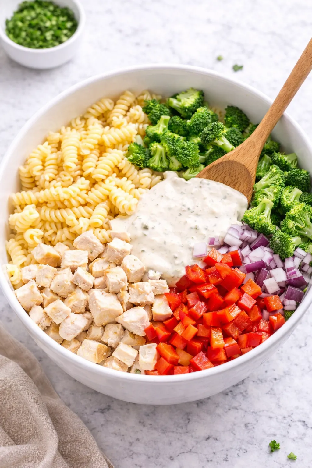 Mixing chicken pasta salad ingredients in a white bowl step 3