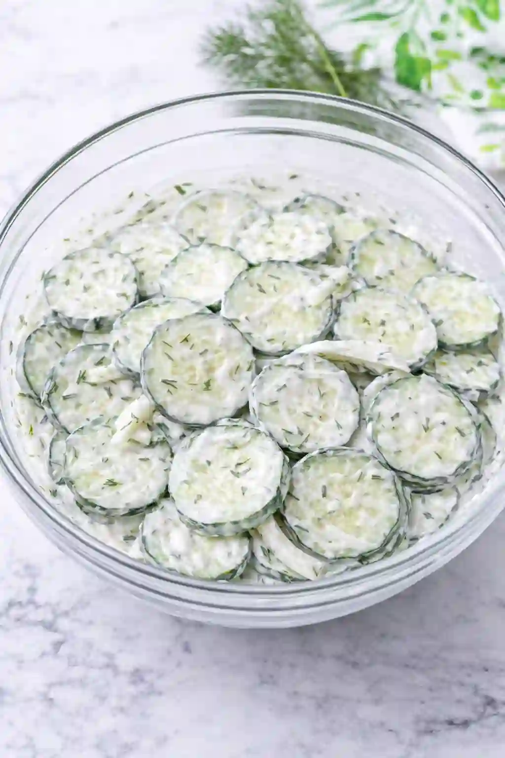 Creamy cucumber salad ready to serve in a bowl with dill and onion