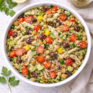 Overhead view of Mediterranean chicken salad with quinoa, chickpeas, tomatoes, olives, cucumber and feta in a white bowl