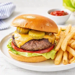 Burger recipes juicy hamburger with cheese pickles on plate with fries