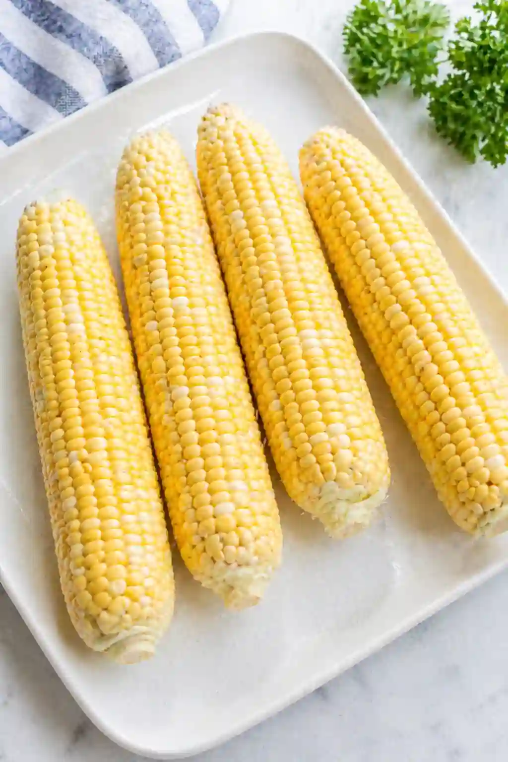 fresh corn on the cob with husks removed on a plate