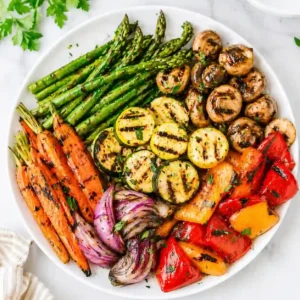 Grilled vegetables recipe on a white plate with asparagus, carrots, peppers, and zucchini