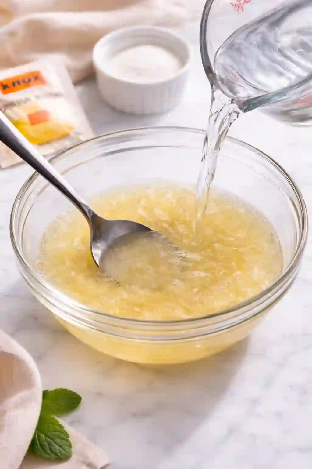  pouring hot water into bloomed gelatin to dissolve it fully