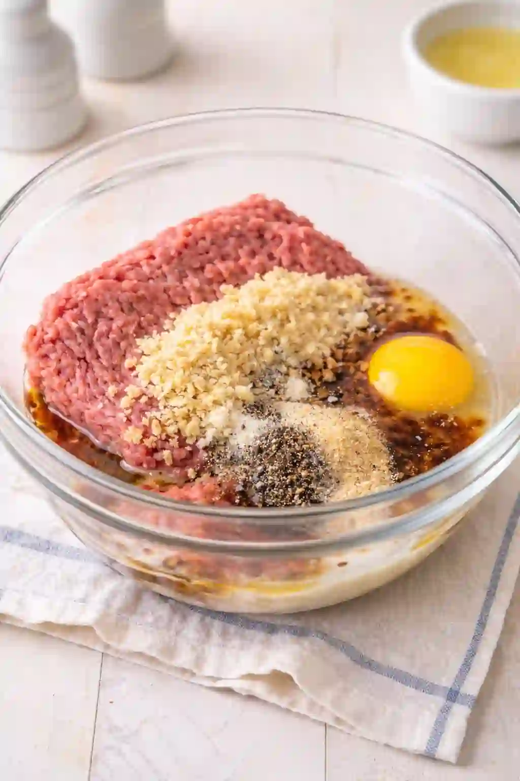 vertical image mixing ground beef egg breadcrumbs milk and Worcestershire sauce in bowl for burger patties