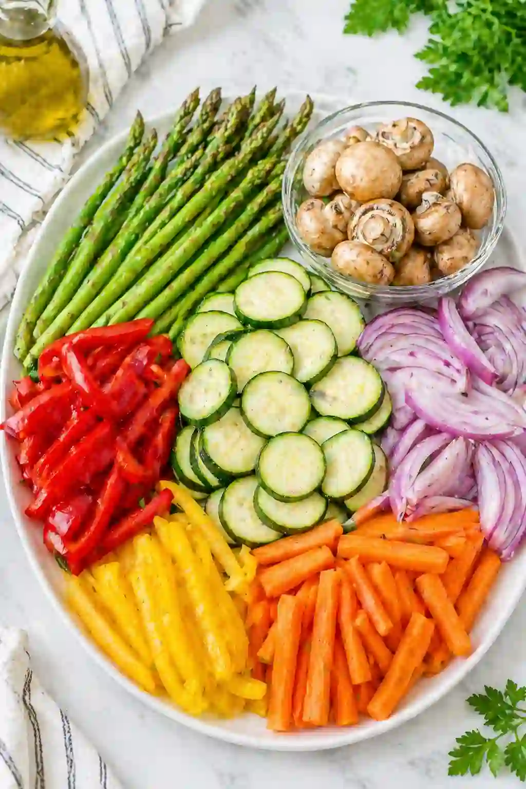 Prepared vegetables for grilled vegetables recipe with sliced zucchini, carrots, peppers, and onions on a plate