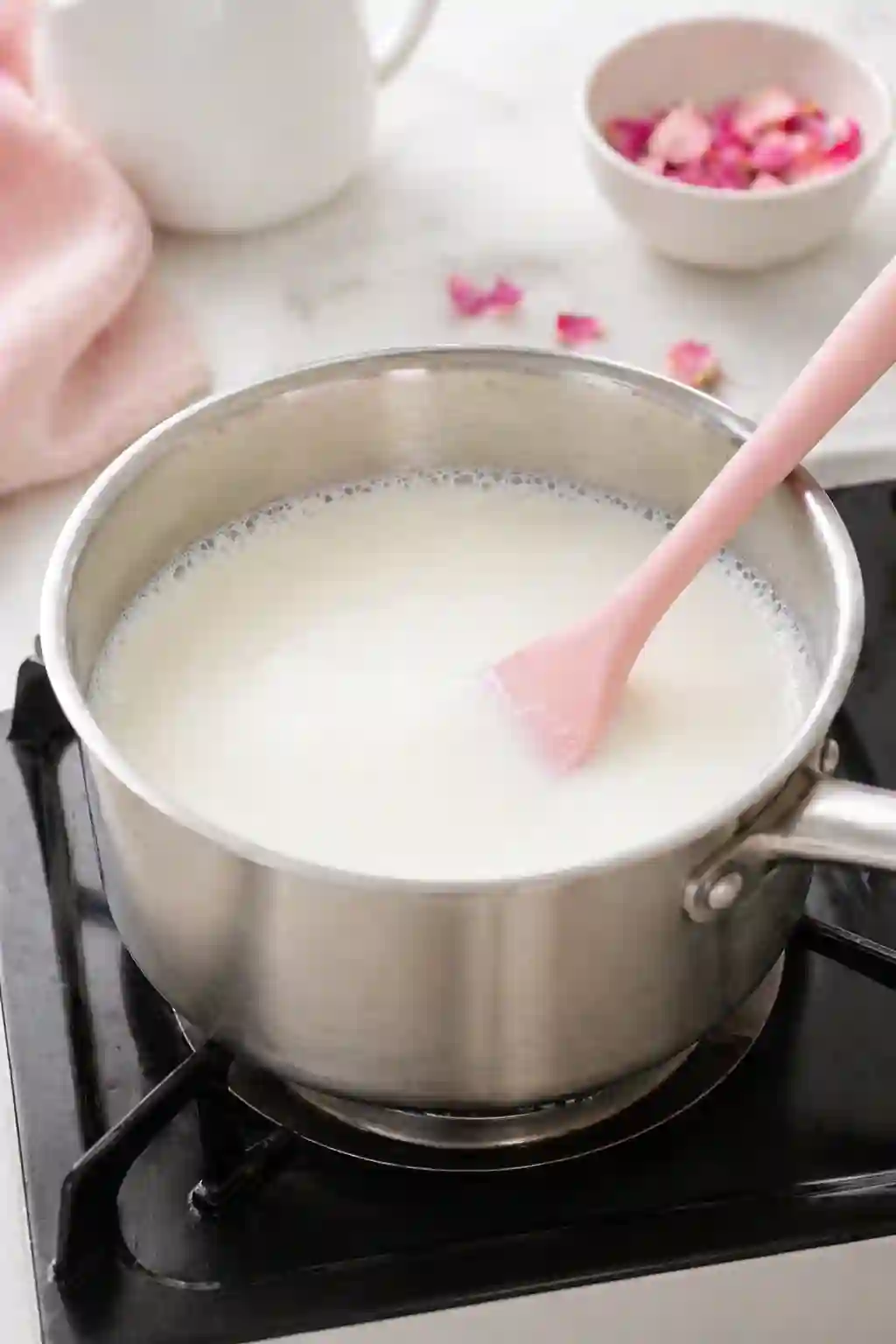 Milk heating gently in a saucepan for rose milk gelatin recipe