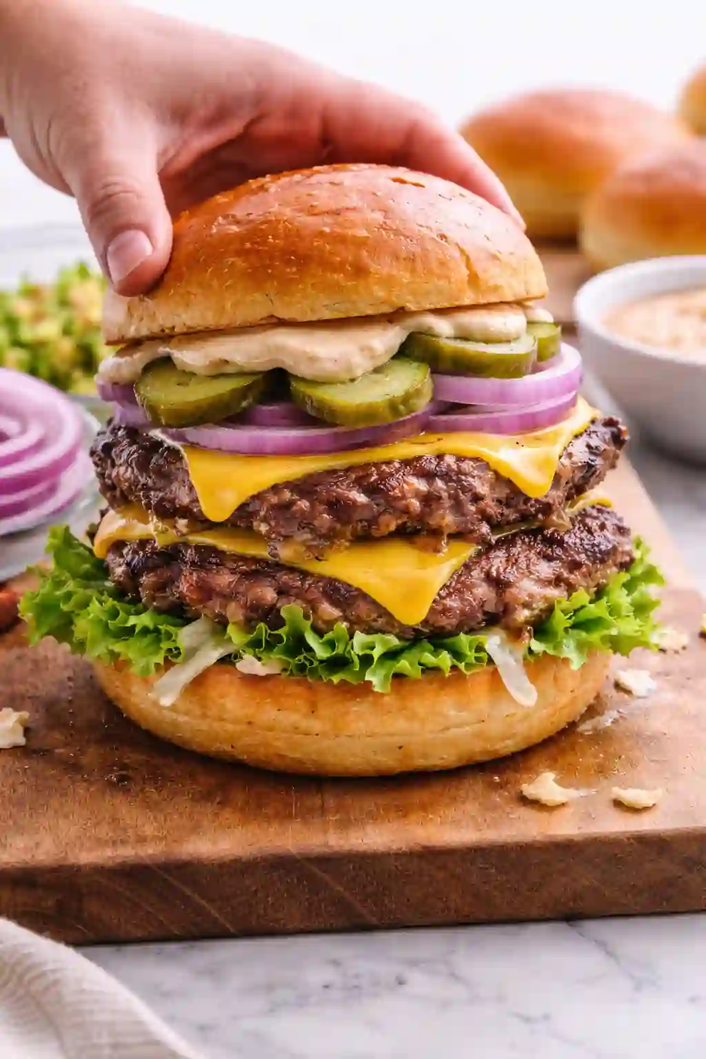 Building a double smash burger with cheese lettuce pickles and sauce