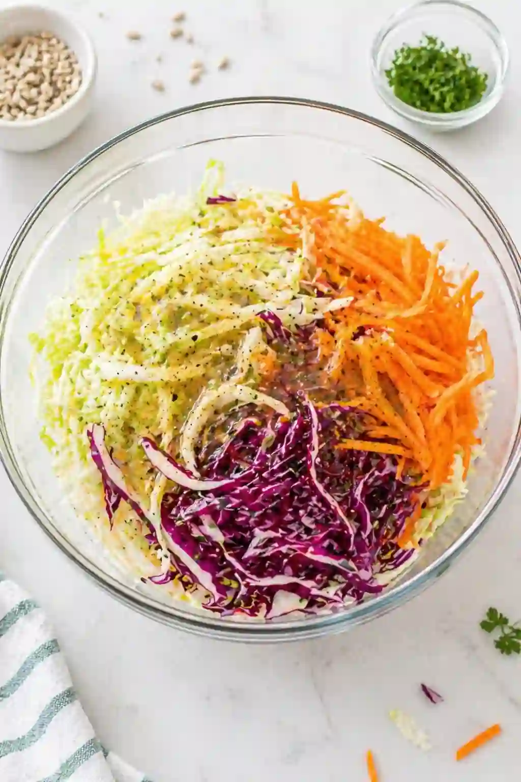 Adding shredded cabbage and carrots to vinegar coleslaw dressing in a bowl
