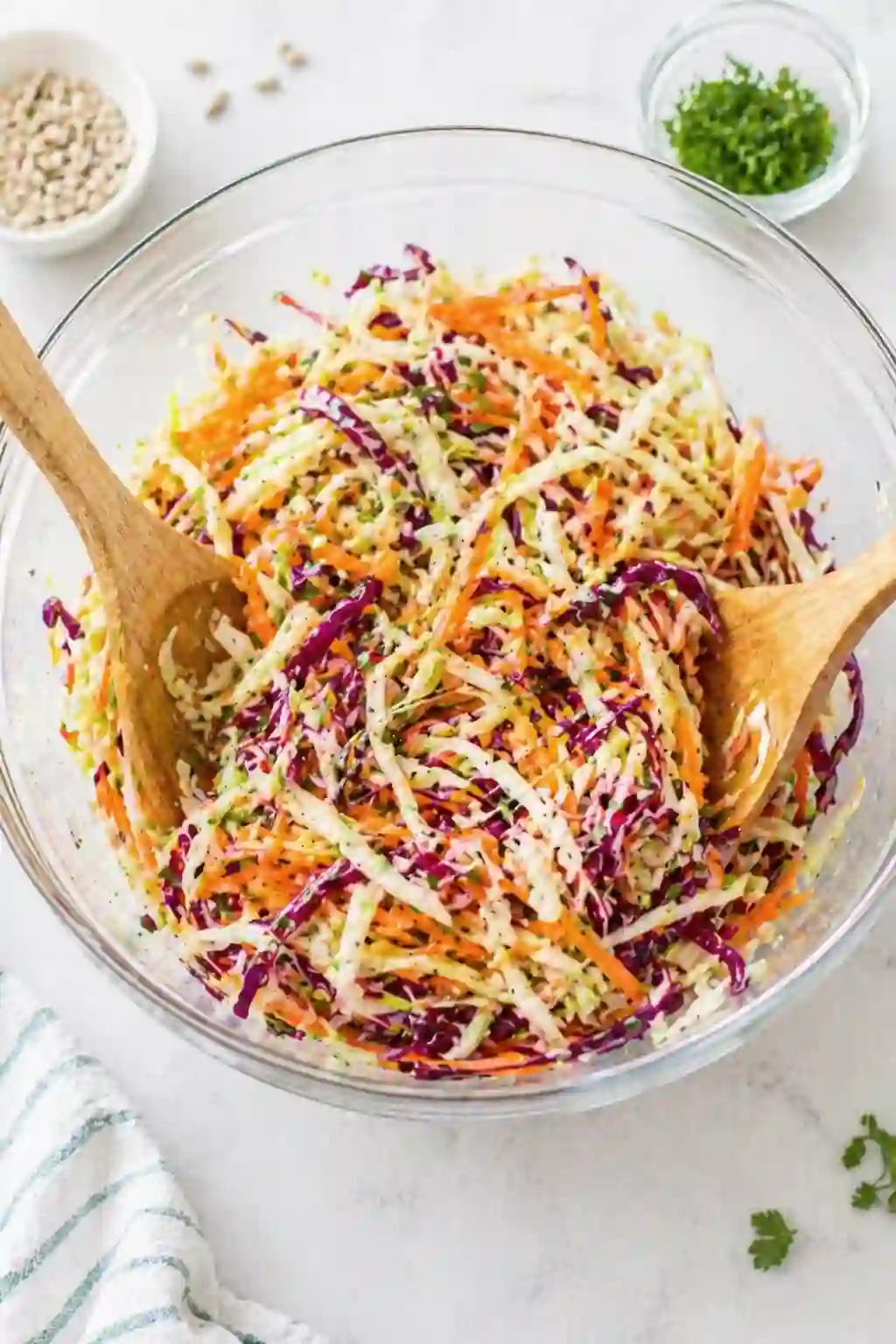 Tossing vinegar coleslaw with shredded cabbage and carrots in a bowl